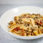 tuscan pasta in a pasta bowl with sun dried tomatoes, sausage, and zucchini