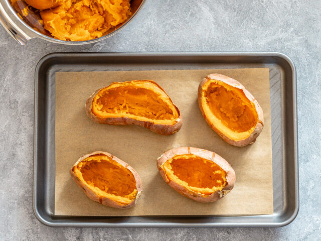 Hollowed sweet potatoes on baking sheet.