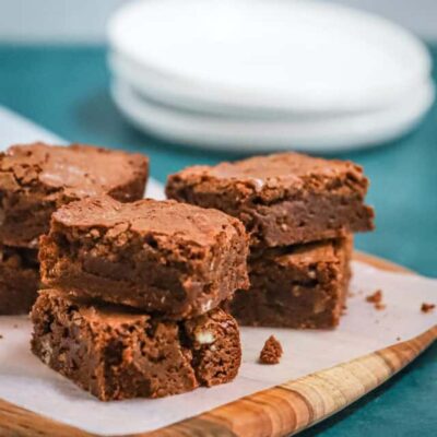 Ultimate fudgy brownies on a parchment paper and teak board, ready to enjoy.