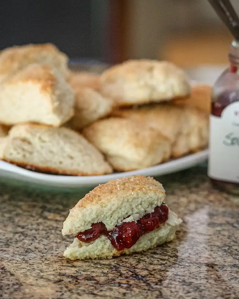 Fluffy scone with cherry jam and whipped cream.