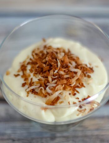 homemade vanilla pudding in a glass dessert dish with toasted coconut