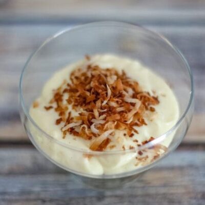 homemade vanilla pudding in a glass dessert dish with toasted coconut