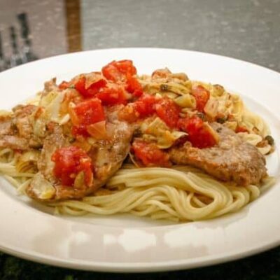 veal cutlets with tomatoes and artichokes on pasta