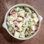 A bowl of Waldorf salad with apples, celery, and nuts.
