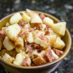 A serving bowl with warm, Cajun flavored potato salad