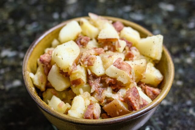 A serving bowl with warm, Cajun flavored potato salad