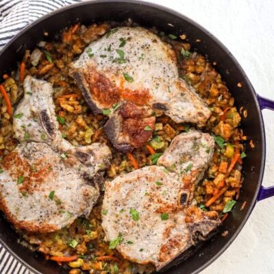 A large Staub saute pan with seasoned stuffing and pork chops baked in the oven.