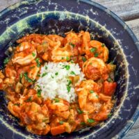 A bowl of shrimp creole with rice and parsley garnish.