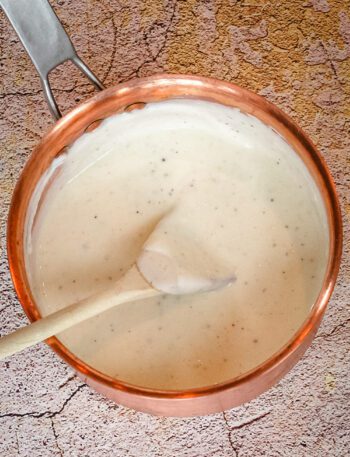 a basic white sauce in a copper saucepan