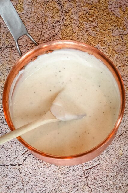 a basic white sauce in a copper saucepan