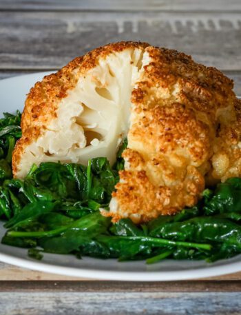 whole roasted cauliflower sliced, on a plate