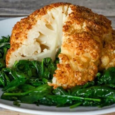 whole roasted cauliflower sliced, on a plate