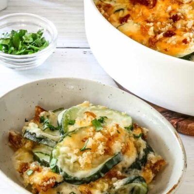 Zucchini casserole on a plate with the baking dish in the