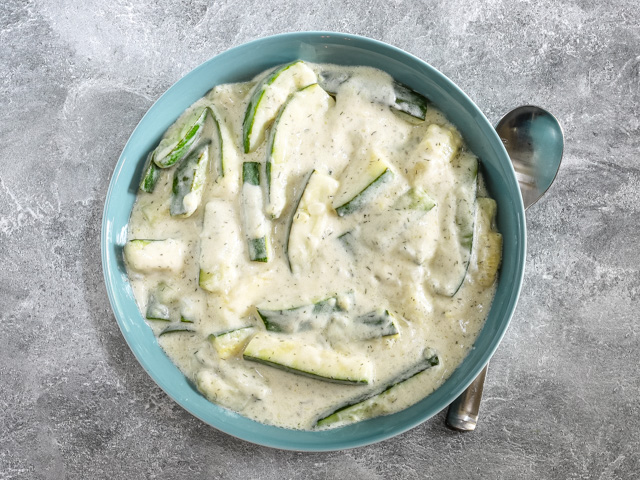 A serving bowl with zucchini in sour cream sauce.